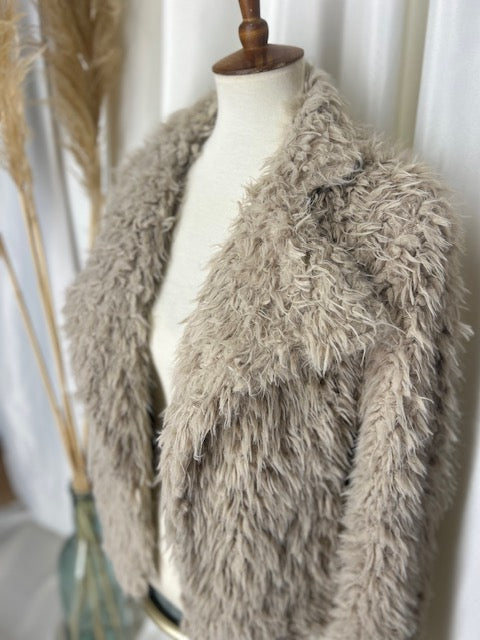 neutral colored bohemian shag jacket on display with a pampas