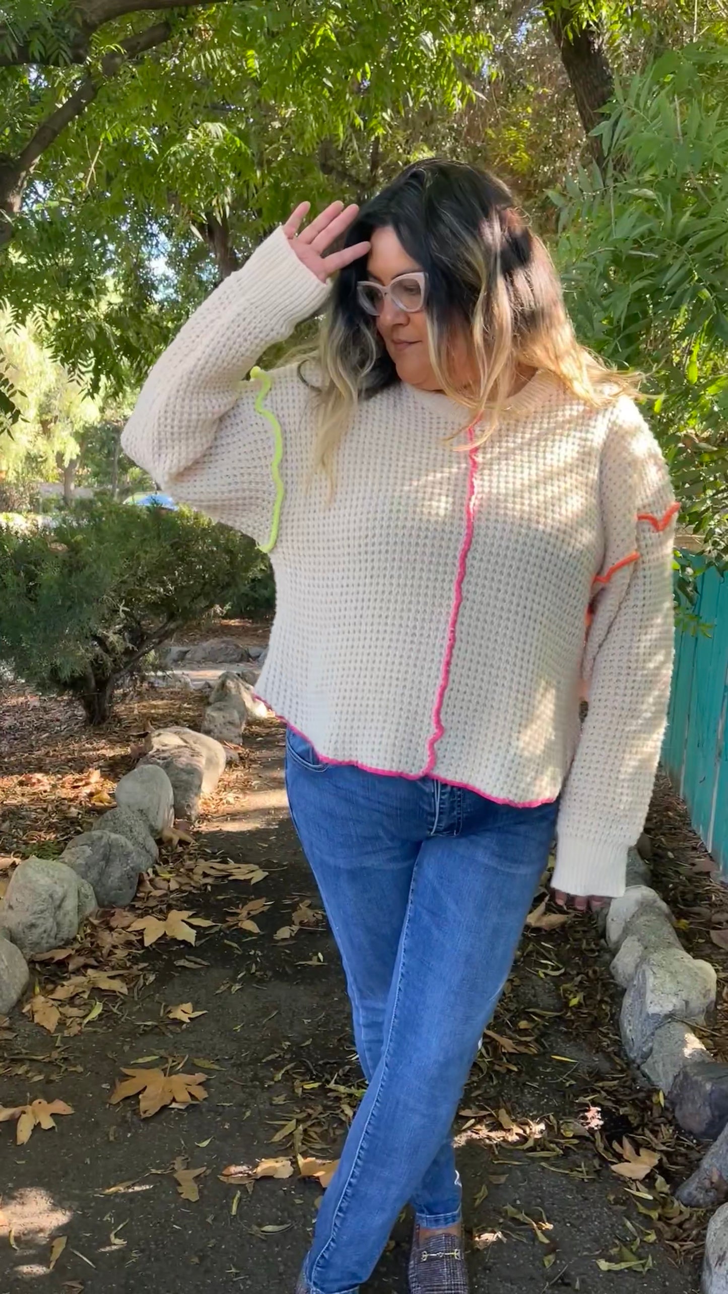 model wearing a large waffle knit cream sweater outside on a trendy walkway