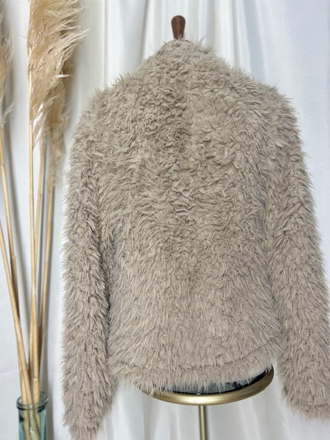 back view of a neutral colored bohemian shag jacket on display with a pampas
